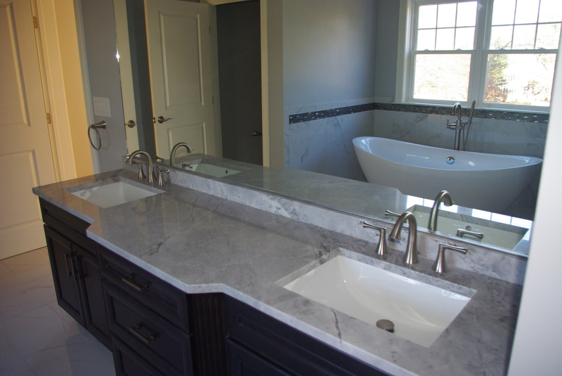 Large, dark double vanity installation with freestanding tub in background