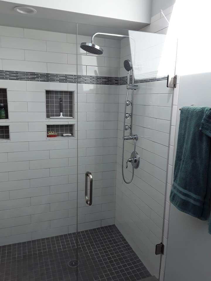 White subway tile with gray tile accents in niche and floor with glass doors