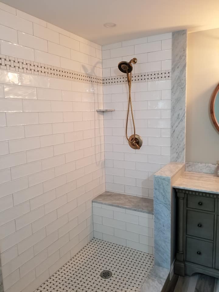 Large walk in shower with gold fixtures and bench